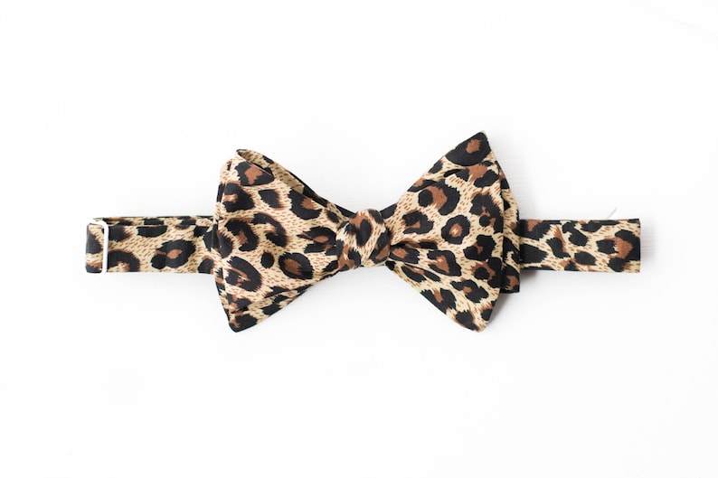May include: A brown and black bow tie with a leopard print pattern.