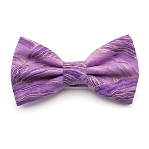 May include: A purple bow tie with a gold and purple marbled pattern.