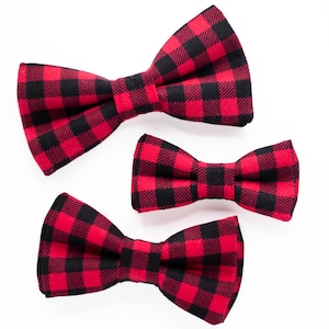 May include: Three red and black plaid bow ties of different sizes. The bow ties are made of a soft, comfortable fabric and are perfect for adding a touch of style to any outfit.