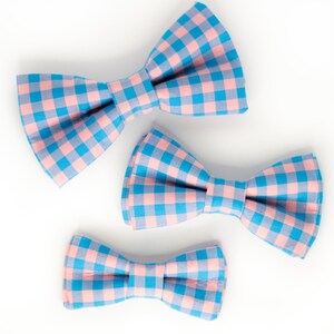 May include: Three gingham bow ties in pink and blue, in different sizes.