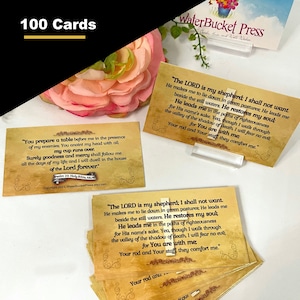 May include: A set of 100 cards with a vintage aesthetic featuring bible verses from Psalm 23. The cards are printed on a textured paper with a yellowed background. The text is in black and brown. The cards are stacked on top of each other. The top card features the verse "The LORD is my shepherd; I shall not want. He makes me to lie down in green pastures; He leads me beside the still waters. He restores my soul."