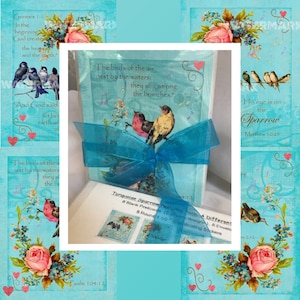 May include: A set of 8 turquoise blue blank postcards with a sparrow design. The cards are packaged in a clear box with a turquoise blue ribbon. The box also includes 8 coordinating stickers and 8 envelopes. The text on the cards reads "The birds of the air nest by the waters; they sing among the branches." and "His eye is on the Sparrow, Matthew 10:29".