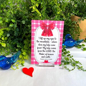 K&ouml;nnte beinhalten: Eine rechteckige Karte mit einem rosa-wei&szlig;en Vichy-Muster, einer roten Schleife oben und einem kleinen roten Herz unten. Der Text lautet: I lift up my eyes to the mountains - where does my help come from? My help comes from the LORD, the Maker of heaven and earth. Psalm 121:1-2 NIV.