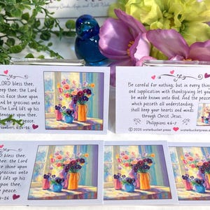 Pode incluir: Cart&otilde;es com arte floral e vers&iacute;culos b&iacute;blicos. Os cart&otilde;es apresentam uma pintura de flores em vasos. O texto nos cart&otilde;es inclui vers&iacute;culos de N&uacute;meros 6:24-26 e Filipenses 4:6-7. Os cart&otilde;es s&atilde;o decorados com cora&ccedil;&otilde;es.