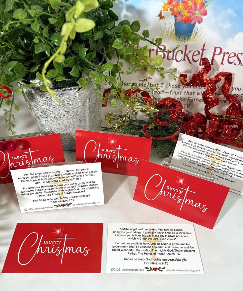 Peut inclure: Cartes de No&euml;l rouges avec l'inscription blanche &laquo; joyeux No&euml;l &raquo; et un motif en forme d'&eacute;clat d'&eacute;toile. Chaque carte comprend un verset biblique. Les cartes sont dispos&eacute;es avec de la verdure et des &eacute;l&eacute;ments d&eacute;coratifs.