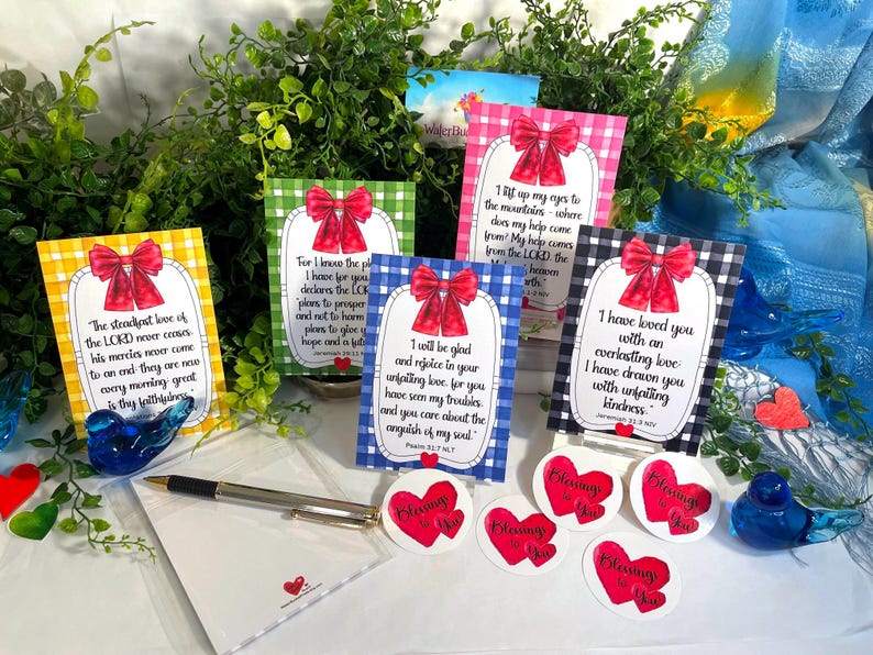 K&ouml;nnte beinhalten: Eine Sammlung von f&uuml;nf rechteckigen Karten mit Vichy-Karomustern in Gelb, Gr&uuml;n, Pink, Blau und Schwarz, jeweils mit einer roten Schleife verziert und mit religi&ouml;sen Texten bedruckt. Enth&auml;lt einen silbernen Stift und herzf&ouml;rmige Aufkleber.