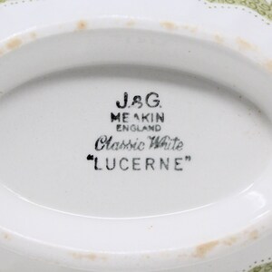 May include: Close-up of the bottom of a white ceramic dish with a green floral pattern. The dish is marked "J&G. MEAKIN ENGLAND Classic White "LUCERNE""