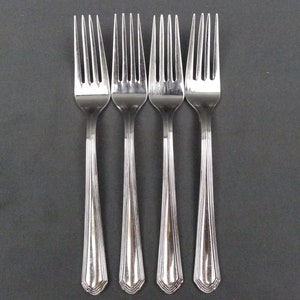 May include: Four silver forks with a decorative design on the handle.