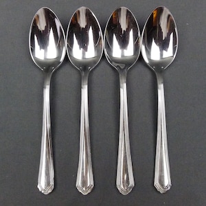 May include: Four silver spoons with a decorative design on the handle.