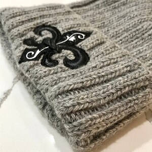 May include: Grey knitted beanie with a black embroidered fleur-de-lis design.