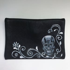 Cartera de piel negra. Cartera sencilla de un bolsillo. Cartera con calavera pintada a mano. Cartera con botón de calavera bañada en plata. Cartera con un bolsillo.