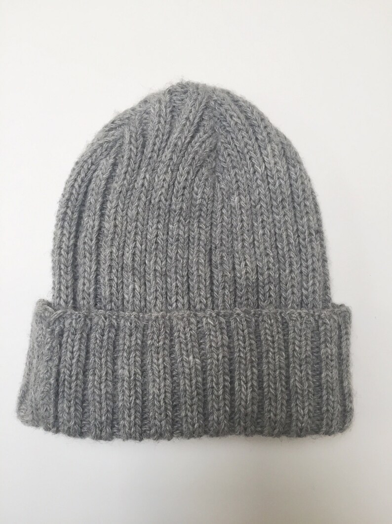 May include: A grey knitted beanie hat with a ribbed texture.