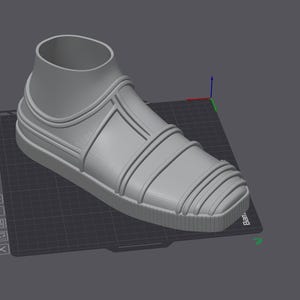May include: A 3D-rendered gray sneaker with a high-top design. The shoe features a rounded toe, a thick sole, and decorative lines across the top. The shoe is set on a dark gray surface with a grid pattern.
