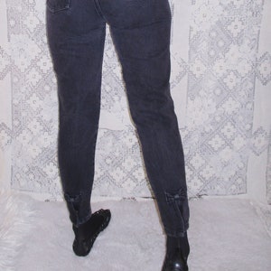May include: Black high-waisted jeans with a dark green velvet top. The jeans have a slight flare at the bottom and a small logo on the back pocket.