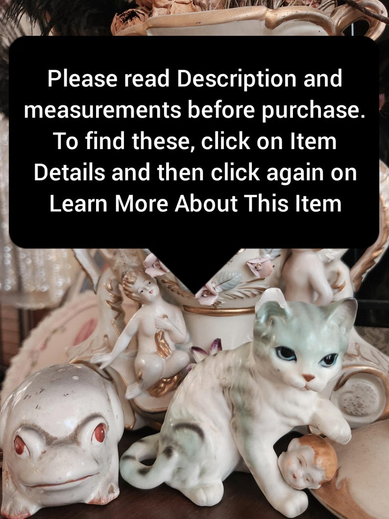 May include: A collection of ceramic figurines, including a cat, a frog, and a nude female figure. The cat is white with blue-green accents and is holding a small doll head. The frog is white with red eyes. The text in the image says to read the description and measurements before purchase.