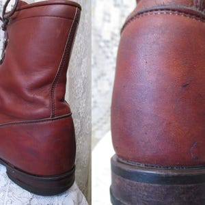 May include: A pair of reddish-brown leather boots. The boots are lace-up style with a rounded toe and a sturdy sole. The leather has a slightly worn appearance, suggesting vintage or well-loved footwear.