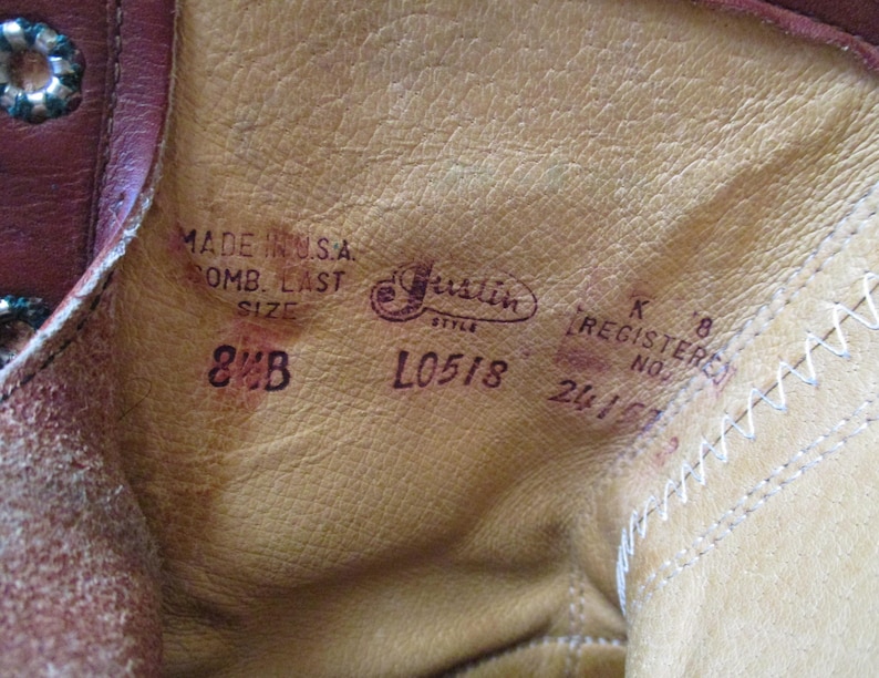 May include: Close-up of the inside of a brown leather boot. The text "MADE IN U.S.A." and "8 B" are visible, along with the brand name "Justin" and style information. The boot's interior is a light tan color.