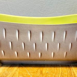 May include: A brown and yellow ceramic planter with a textured design. The planter has a rectangular shape with rounded edges.