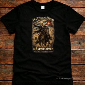 May include: Black t-shirt featuring a sepia-toned illustration of Máximo Gómez on horseback, holding a flag. The text "EL GENERALÍSIMO" and "MÁXIMO GÓMEZ" are above and below the image, with additional text below. The shirt is made of a soft material.