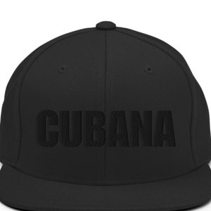 May include: A black flat brimmed baseball cap with the word 'CUBANA' embroidered in black on the front.