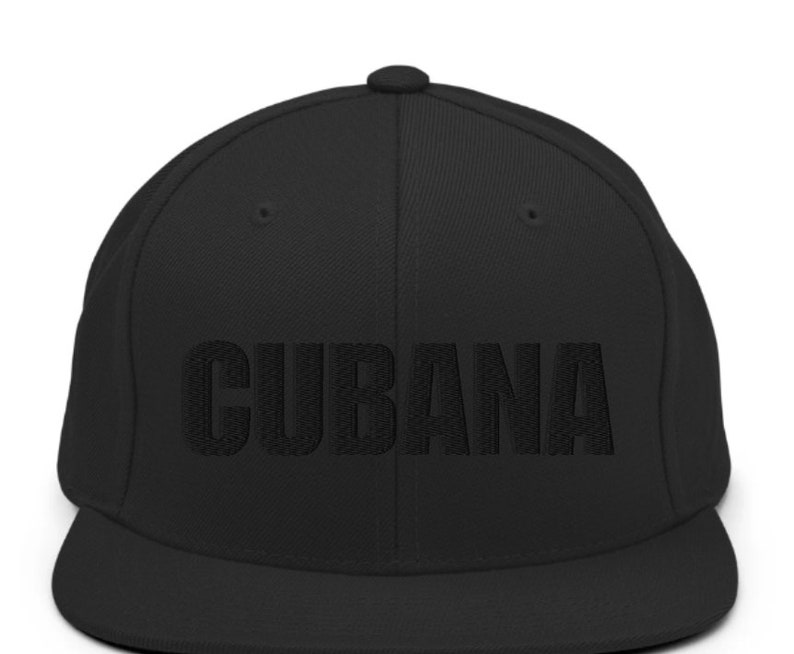 May include: A black flat brimmed baseball cap with the word 'CUBANA' embroidered in black on the front.