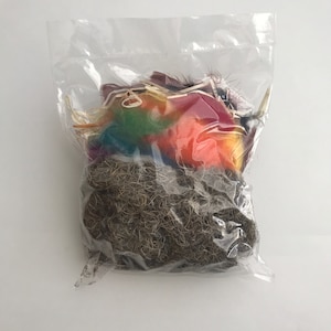 May include: A clear plastic bag filled with colorful feathers and brown dried moss.