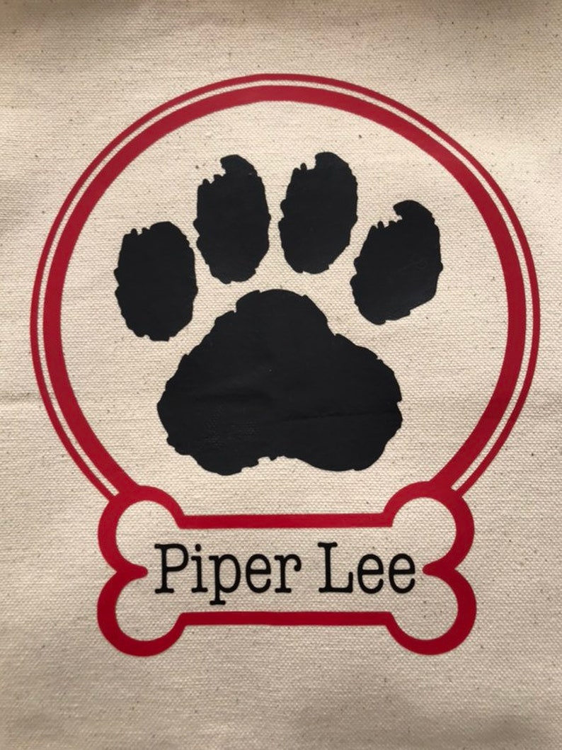 May include: A red bone-shaped design with the name "Piper Lee" printed in black text. A black paw print is inside a red circle.
