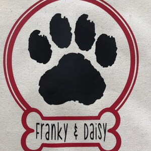 May include: A red bone-shaped design with a black paw print inside a red circle. The text "Franky & Daisy" is written inside the bone.