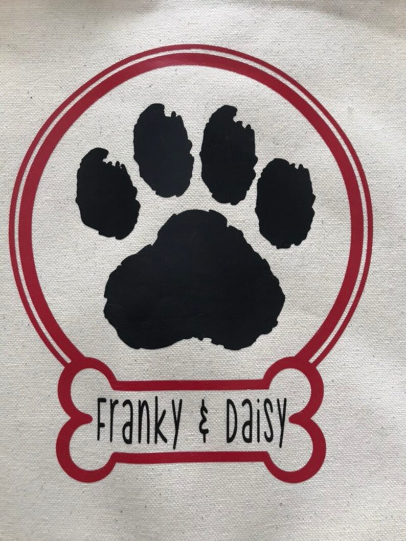 May include: A red bone-shaped design with a black paw print inside a red circle. The text "Franky & Daisy" is written inside the bone.