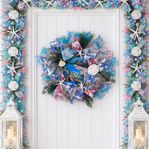 May include: A coastal-themed wreath with a mermaid and sea turtle image at the center, surrounded by blue, white, and pink ribbons, starfish, and greenery. Matching garland with starfish and sand dollars frames the door. White lanterns with candles complete the beachy decor.