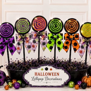 May include: Six decorative lollipops on sticks, each featuring a spiral pattern in purple, green, or orange, accented with patterned bows. A central sign reads HALLOWEEN Lollipop Decorations, surrounded by small glittery spheres and pumpkins.