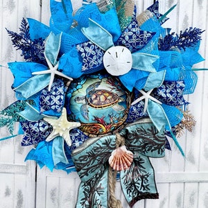May include: A blue and white wreath with a sea turtle, starfish, and seashells. The wreath is decorated with blue and white ribbon and a brown bow.
