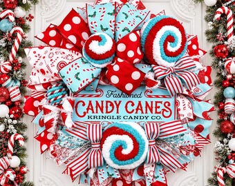 May include: A decorative Christmas wreath featuring red and white polka dot ribbons, light blue ribbons with candy cane patterns, and three plush red and white swirl ornaments. A central sign reads "Fashioned CANDY CANES KRINGLE CANDY CO."