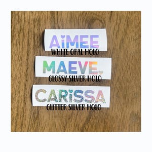 three stickers with different colors and designs, placed on a wooden surface.
