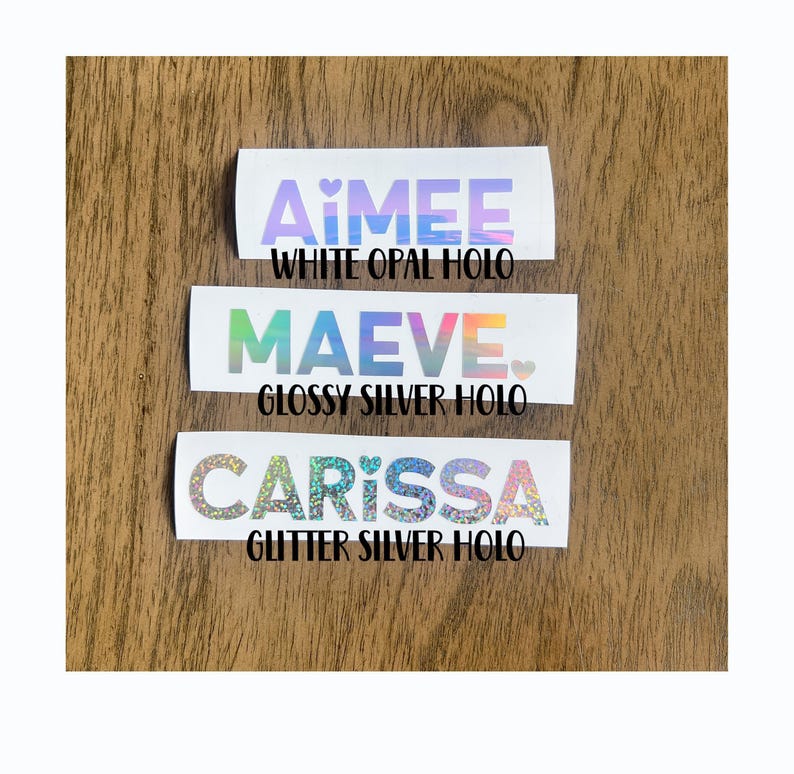 three stickers with different colors and designs, placed on a wooden surface.