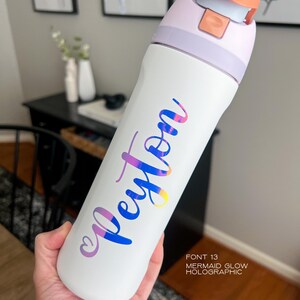 A person's hand holding a white water bottle with the name "Peyton" printed on it in a stylized font.