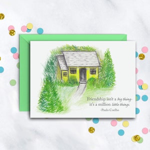 May include: A yellow house with a black door and a gray roof is surrounded by green trees. The quote "Friendship isn't a big thing - it's a million little things. - Paulo Coelho" is printed below the house.