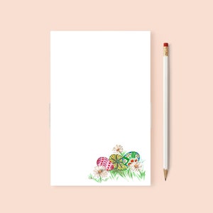 May include: A blank white notepad with a pencil and a hand-drawn illustration of Easter eggs and flowers at the bottom.