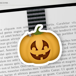 Può includere: Una zucca di Halloween gialla con un viso intagliato e un piccolo ragno in cima. La zucca è su un libro con il testo "Petit Creaciones" visibile.