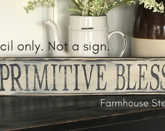 May include: A white wooden sign with black lettering that reads "PRIMITIVE BLESSINGS". The sign is distressed and has a rustic look. The sign is on a black surface with a white background.