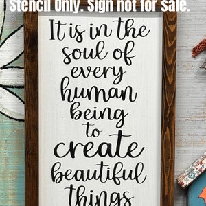 May include: A white wooden sign with a brown frame, featuring the text "It is in the soul of every human being to create beautiful things". The sign also includes the text "Farmhouse Stencil Shoppe".