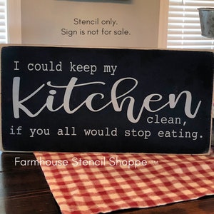 May include: Black wooden sign with white text that reads "I could keep my kitchen clean, if you all would stop eating." The sign has the text "Farmhouse Stencil Shoppe" at the bottom.