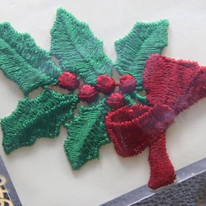 May include: Embroidered holly leaf and berry applique with a red bow. The green leaves and red berries are detailed with textured stitching. This festive applique is suitable for holiday crafts and decorations.