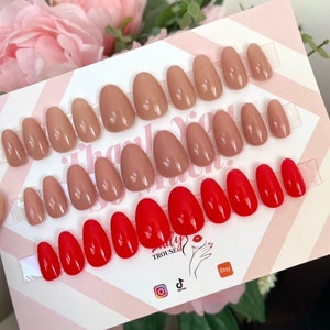 Könnte beinhalten: Ein Set mit 20 ovalen Press-on-Nägeln. Die Nägel sind in zwei Farben: Nude und Rot. Die Nägel sind in Reihen auf einer weißen Karte mit rosa und weißen Streifen angeordnet. Die Karte trägt den Text "Dally Trousse" und Social-Media-Symbole.