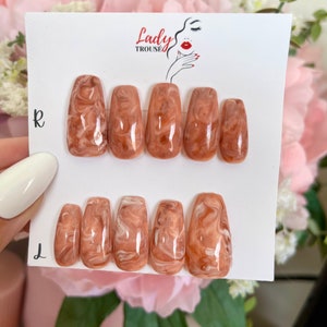 May include: A set of 10 false nails with a marbled design in shades of brown and white. The nails are arranged in two rows, labeled "R" and "L" for right and left hands. The nails are displayed on a white card with the text "Lady Trouse" printed on it.