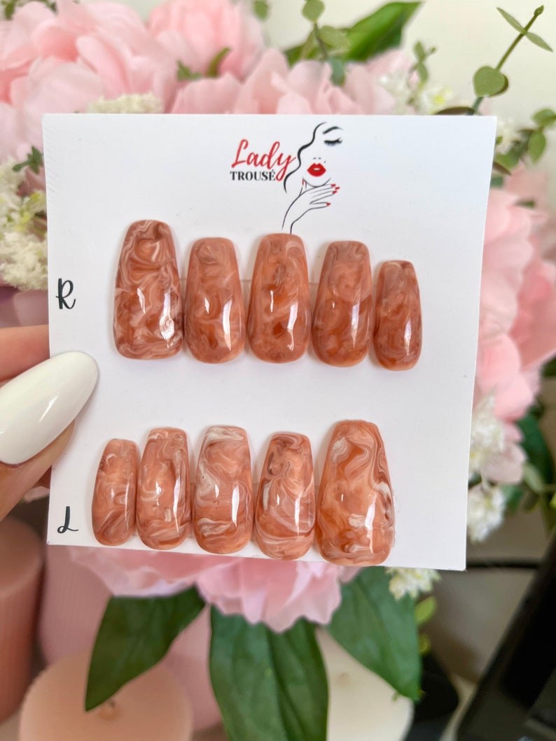 May include: A set of 10 false nails with a marbled design in shades of brown and white. The nails are arranged in two rows, labeled "R" and "L" for right and left hands. The nails are displayed on a white card with the text "Lady Trouse" printed on it.
