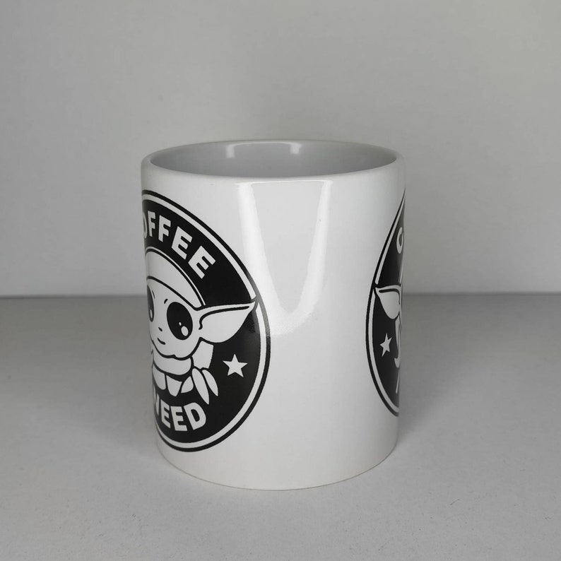 Pu&ograve; includere: Tazza da caff&egrave; in ceramica bianca con una grafica in bianco e nero di un personaggio dei cartoni animati con il testo "Coffee and Weed" in un cerchio.