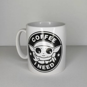 Pu&ograve; includere: Tazza in ceramica bianca con una grafica in bianco e nero di un personaggio dei cartoni animati con il testo "COFFEE I NEED" in un cerchio.