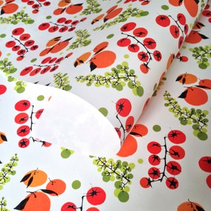 May include: White wrapping paper with a repeating pattern of red tomatoes on green vines and orange fruit. The paper is folded over on itself, revealing the white underside.