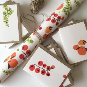 May include: A stack of blank greeting cards with brown envelopes. The cards feature a variety of colorful illustrations, including grapes, tomatoes, and oranges. The cards are perfect for sending a handwritten note to a loved one.